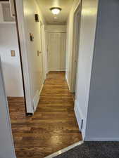 Hallway featuring dark wood finished floors and baseboards