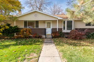 View of front of property with brick & siding, a front yard, and covered porch