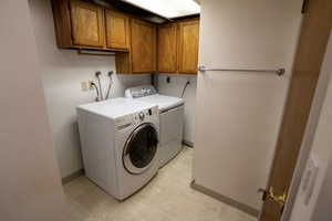 Washroom featuring cabinet space, washing machine and clothes dryer, and light floors