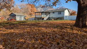 Rear view of house with stairs, a storage unit, and a deck with mature landscape and mountain view
