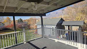 Covered patio with ceiling fan, outbuildings and a mountain view