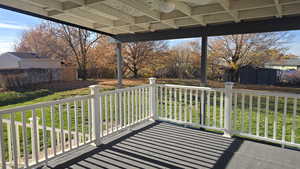 Spacious Covered patio featuring a ceiling fan, fenced backyard with mature trees and out buildings.