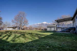 View of green lawn, fully fenced featuring a covered patio, 3 outbuildings with mountain views