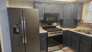 Kitchen featuring appliances with stainless steel finishes, gas range, light countertops, and backsplash