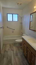 Full bathroom with vanity, dark wood finished floors, bathtub / shower combination.
