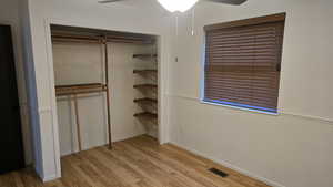 Primary bedroom closet view, featuring light wood-style floors, a closet, and ceiling fan