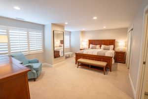 Primary Bedroom with recessed lighting, light carpet, and a closet