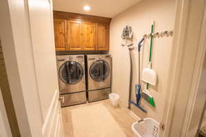 Laundry area with cabinet space, washer and clothes dryer, and light wood-style floors