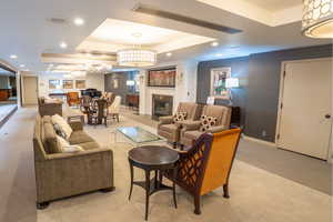 Community Living room with a tray ceiling, recessed lighting, light colored carpet, wallpapered walls, and a tile fireplace