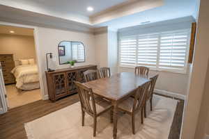 Dining space with a tray ceiling, crown molding, wood finished floors, and recessed lighting