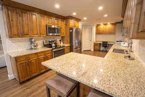 Kitchen featuring backsplash, a peninsula, upgraded cabinetry and recessed lighting