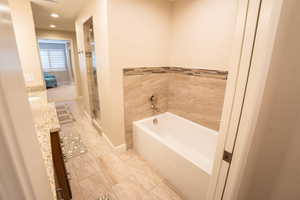 Full bath featuring a bath, vanity, recessed lighting, light tile patterned floors, and a stall shower