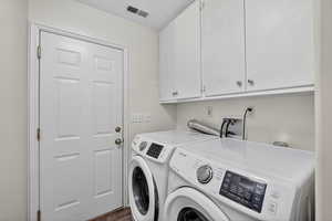 Washroom featuring cabinet space, washing machine and clothes dryer, and dark wood-style floors