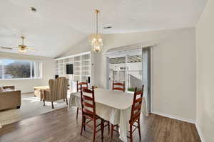 Dining space featuring plenty of natural light, wood finished floors, a chandelier, vaulted ceiling, and a ceiling fan