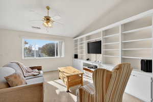 Carpeted living room featuring vaulted ceiling and ceiling fan