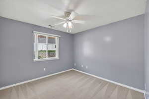 Spare room with light colored carpet, a textured ceiling, and ceiling fan