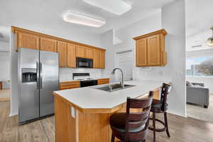 Kitchen with light countertops, stainless steel refrigerator with ice dispenser, lofted ceiling, a peninsula, and a breakfast bar area