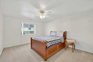 Bedroom with light colored carpet, a ceiling fan, and a textured ceiling