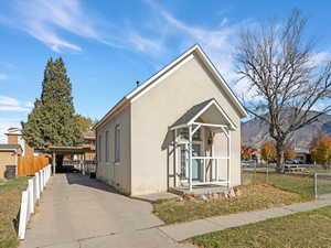 View of front of house featuring stucco siding, concrete driveway, a carport, a mountain view, and a shingled roof