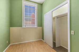 Unfurnished bedroom with a wainscoted wall, light wood-style floors, a closet, and wooden walls