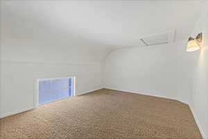 Bonus room featuring attic access, vaulted ceiling, and carpet