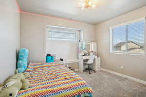 Bedroom featuring light colored carpet, an office area, and a chandelier