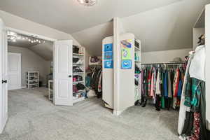 Spacious closet with light colored carpet and lofted ceiling