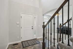 Foyer entrance featuring arched walkways, stairway, and dark stone finish flooring