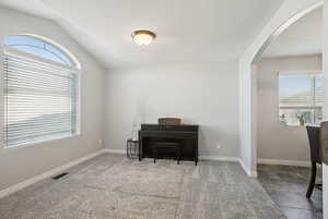 Living area with arched walkways, plenty of natural light, and lofted ceiling
