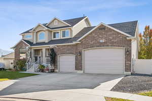 Traditional-style home featuring concrete driveway, brick siding, roof with shingles, and covered porch