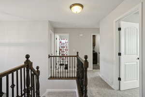 Hall with an upstairs landing, light carpet, and washer / clothes dryer