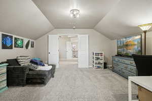 Living area with a textured ceiling, light colored carpet, and vaulted ceiling