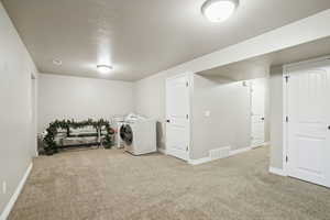 Laundry room featuring carpet flooring, a textured ceiling, and separate washer and dryer