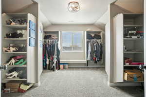 Spacious closet with light colored carpet and lofted ceiling