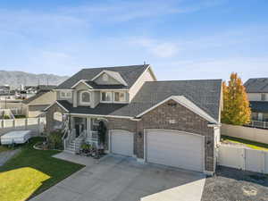 Traditional home with driveway, a porch, a shingled roof, brick siding, and a garage