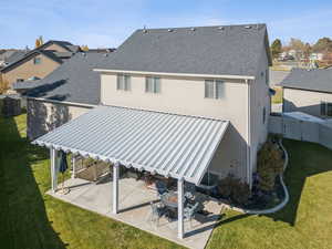 Back of house featuring a patio, a lawn, and a shingled roof