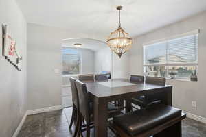 Dining area featuring stone tile floors, arched walkways, and a chandelier