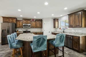 Kitchen with a kitchen bar, stainless steel appliances, recessed lighting, dark brown cabinetry, and a center island