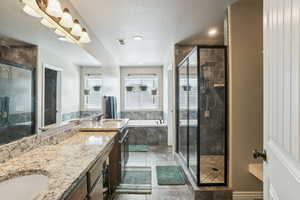 Bathroom with a garden tub, double vanity, a shower stall, a textured ceiling, and light tile patterned flooring