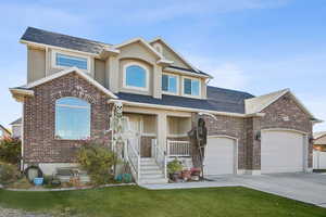View of front of home featuring brick siding, driveway, a shingled roof, and a front yard
