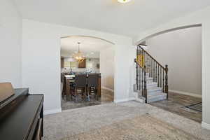 Dining room with arched walkways, stairway, recessed lighting, light colored carpet, and a chandelier