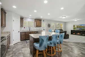 Kitchen with a breakfast bar, open floor plan, dark brown cabinetry, appliances with stainless steel finishes, and recessed lighting
