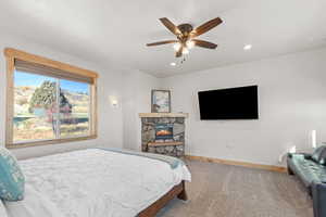 Bedroom with a stone fireplace, carpet flooring, a ceiling fan, and recessed lighting