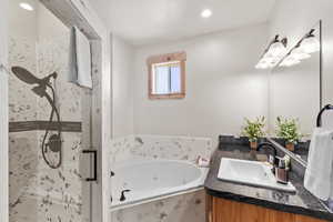 Full bathroom with vanity, a stall shower, a whirlpool tub, and recessed lighting