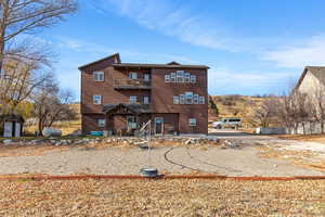 View of front facade featuring faux log siding, a patio area, and a balcony