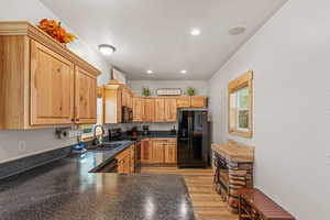 Kitchen featuring black appliances, light wood-style flooring, plenty of natural light, recessed lighting, and light brown cabinets