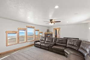 Living area featuring carpet floors, a stone fireplace, recessed lighting, and a ceiling fan