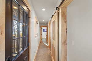 Hallway featuring light carpet, recessed lighting, and a barn door
