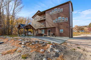 Back of property featuring a patio area, a balcony, and log veneer siding