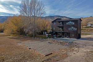 Back of house with a patio area, faux log siding, and a mountain view
